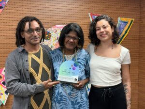 No centro, Luciane segura o troféu. Ao lado dela estão Luan Cândido e Maíra Carvalho.